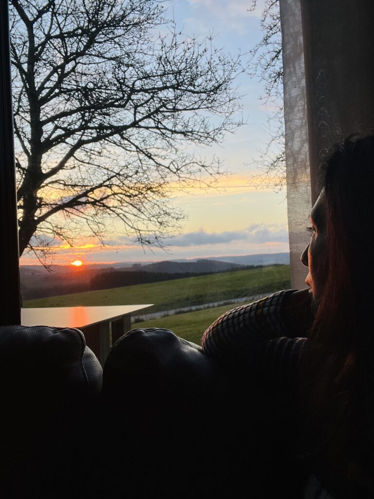 Mujer viendo el atardecer desde la ventana